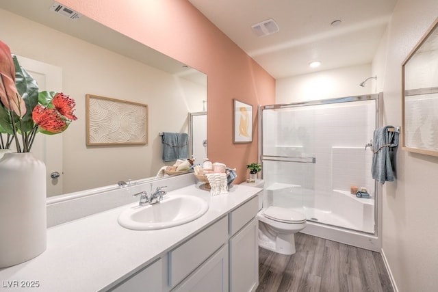 full bathroom with visible vents, a shower stall, wood finished floors, vanity, and toilet