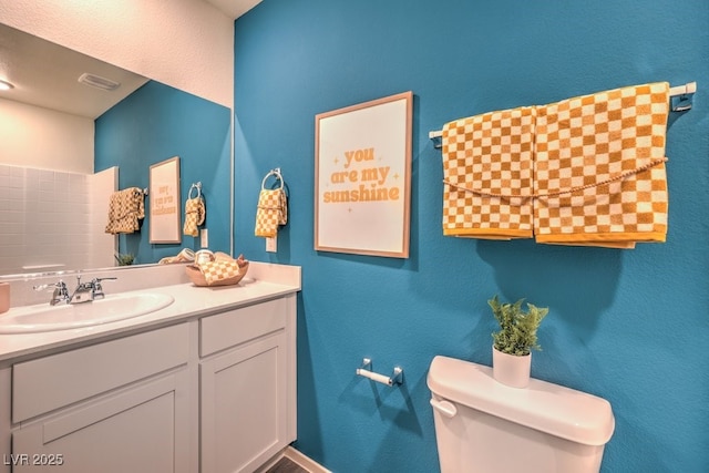 bathroom with vanity, toilet, and visible vents