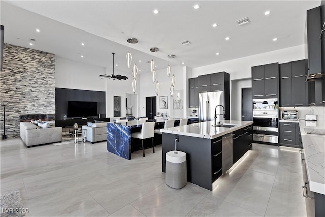 kitchen with visible vents, modern cabinets, a spacious island, a sink, and stainless steel appliances