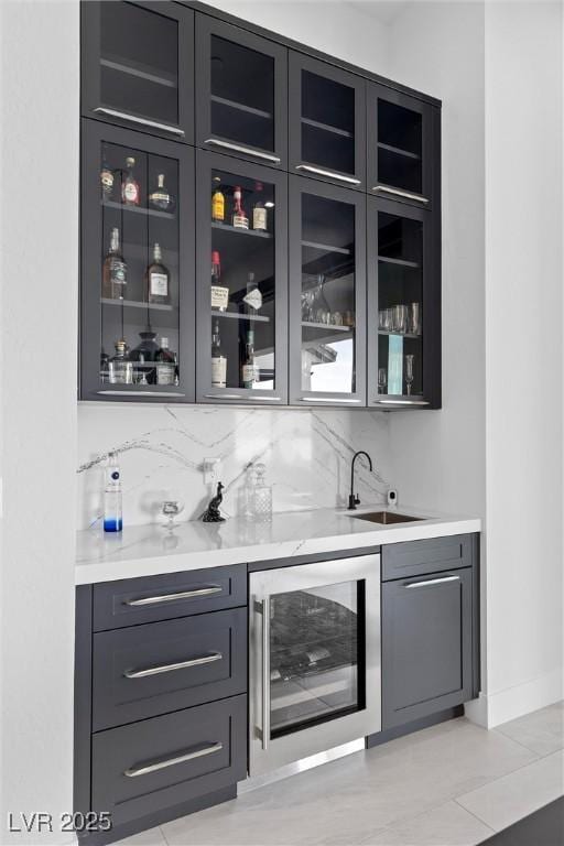 bar with a sink, indoor wet bar, baseboards, tasteful backsplash, and wine cooler
