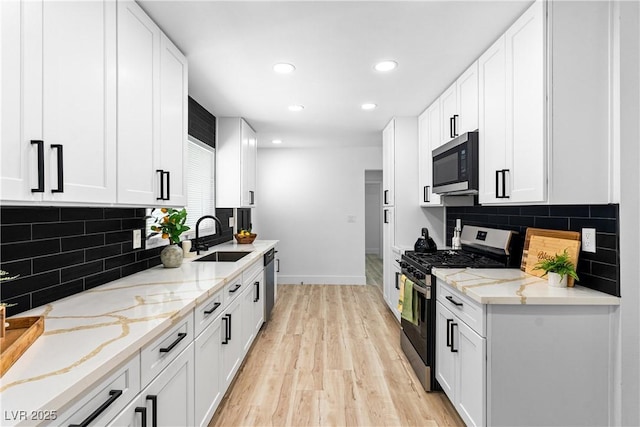 1020 Baker Ave, Las Vegas, NV 89108 - kitchen with a sink, light wood-style flooring, stainless steel appliances, baseboards, and decorative backsplash