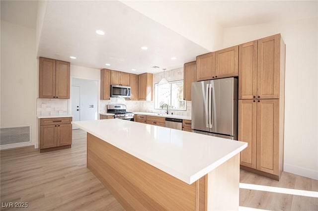 kitchen with visible vents, decorative backsplash, light wood-type flooring, a sink, and stainless steel appliances