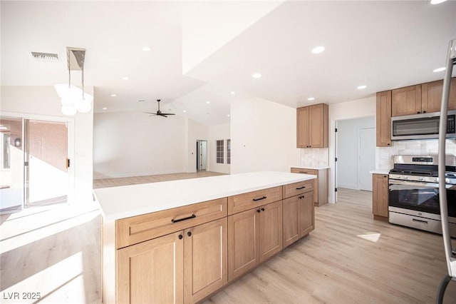 kitchen with lofted ceiling, light wood-style floors, ceiling fan, appliances with stainless steel finishes, and backsplash