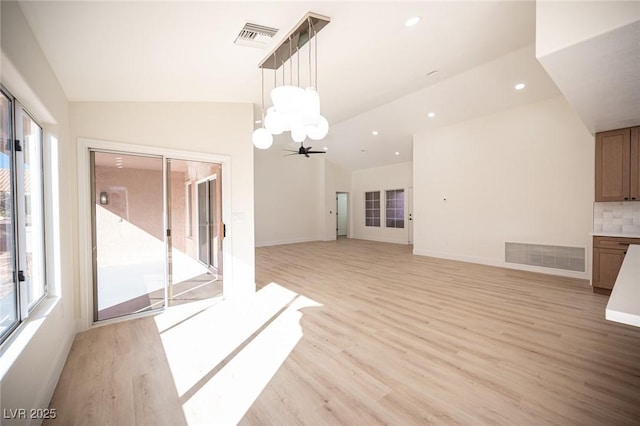 interior space with visible vents, lofted ceiling, light wood-style flooring, and an inviting chandelier