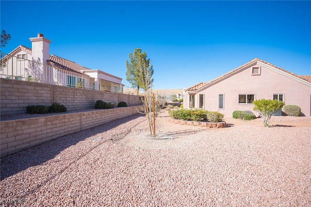 view of side of home featuring a fenced backyard and stucco siding