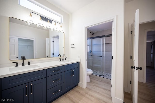 full bath with a sink, a stall shower, and wood finished floors