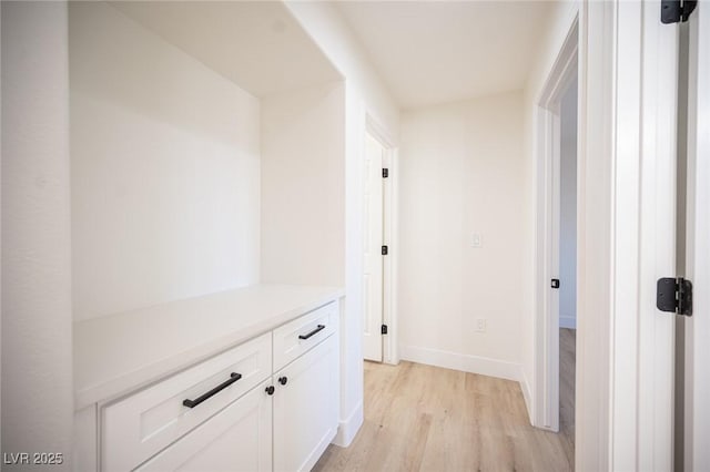 hall with baseboards and light wood finished floors