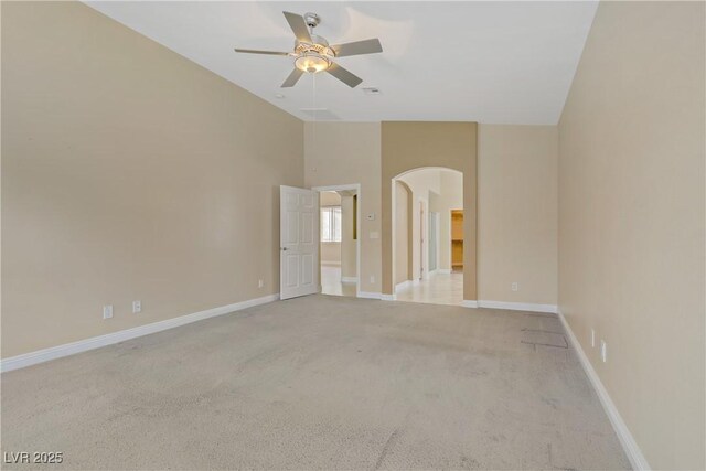 carpeted spare room with arched walkways, ceiling fan, baseboards, and high vaulted ceiling
