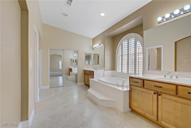 bathroom with a sink, tile patterned flooring, a garden tub, and visible vents