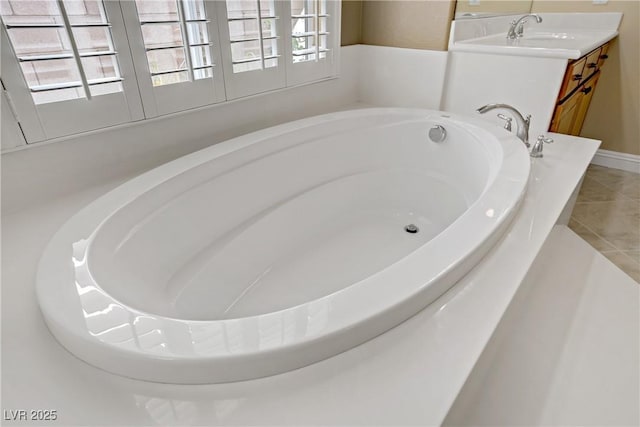 bathroom featuring tile patterned flooring, plenty of natural light, a sink, and a garden tub