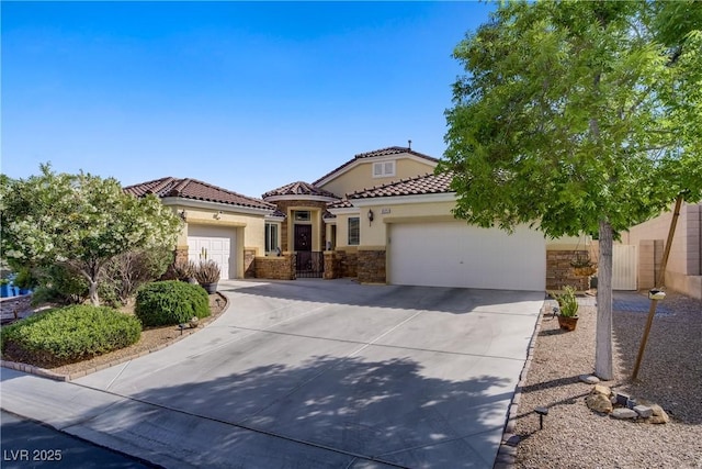 mediterranean / spanish house with concrete driveway, stucco siding, stone siding, and a garage