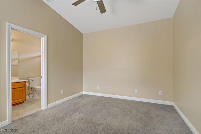 unfurnished bedroom featuring connected bathroom, baseboards, vaulted ceiling, and light carpet
