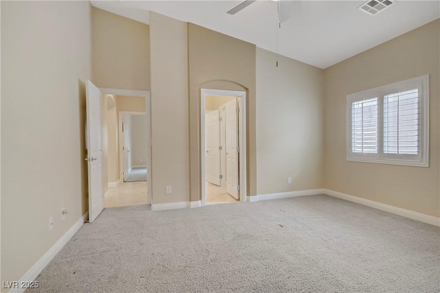unfurnished bedroom featuring baseboards, light colored carpet, connected bathroom, and visible vents