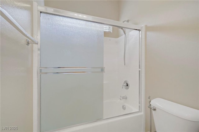 bathroom featuring toilet and bath / shower combo with glass door