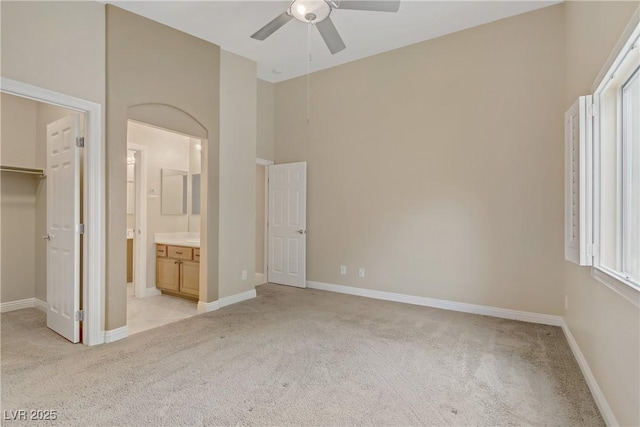 unfurnished bedroom featuring baseboards, a towering ceiling, a walk in closet, and light carpet