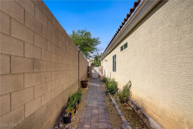 view of property exterior featuring fence, stucco siding, and a tiled roof