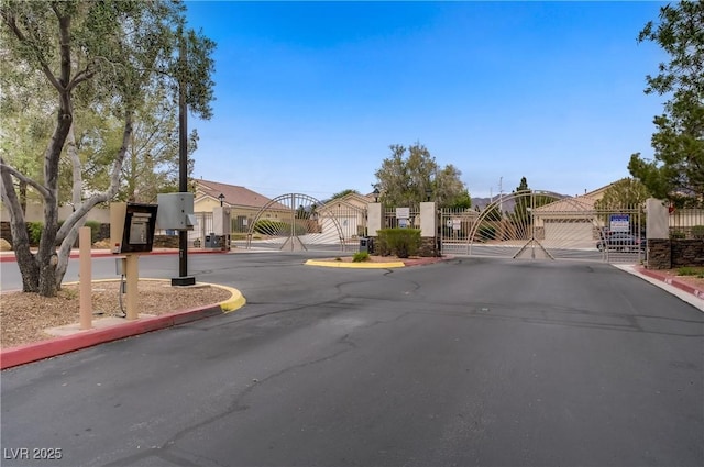 view of street with a gate, a gated entry, curbs, and a residential view