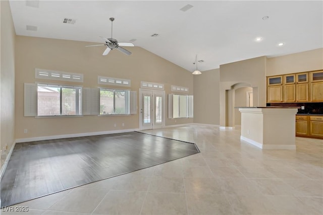 unfurnished living room with visible vents, ceiling fan, a wealth of natural light, and high vaulted ceiling
