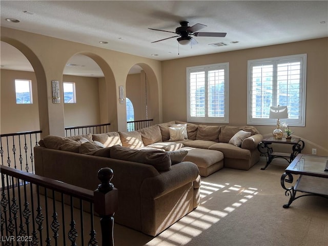 carpeted living room featuring a ceiling fan, visible vents, and a wealth of natural light