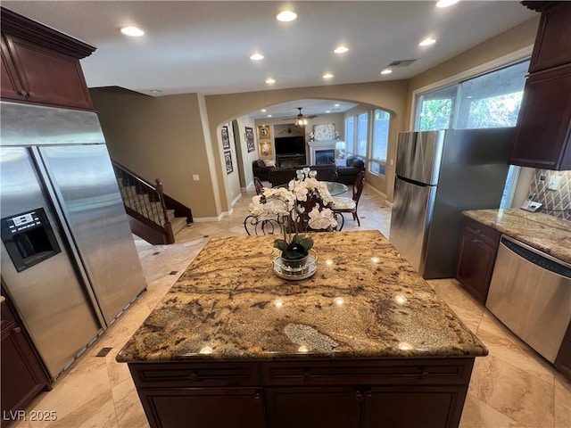 kitchen featuring visible vents, recessed lighting, arched walkways, dark stone countertops, and stainless steel appliances