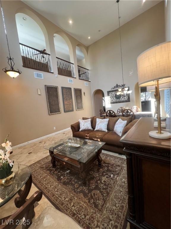 living room with visible vents, arched walkways, baseboards, and a high ceiling
