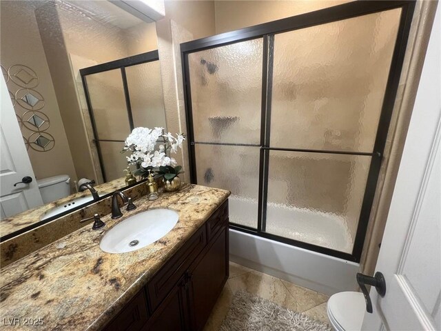 bathroom featuring vanity, tile patterned floors, combined bath / shower with glass door, and toilet