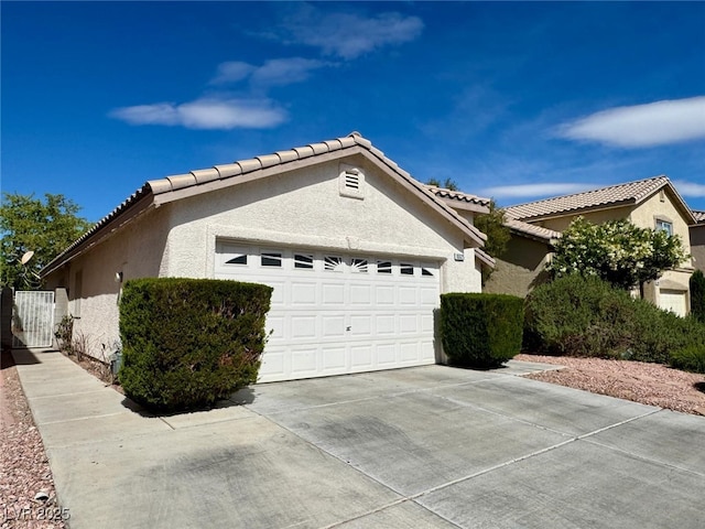 10025 Catseye Cove Ct, Las Vegas, NV 89183 - view of property exterior featuring an attached garage, stucco siding, driveway, and a tile roof