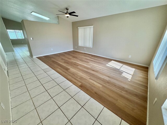 10025 Catseye Cove Ct, Las Vegas, NV 89183 - empty room with a ceiling fan, baseboards, vaulted ceiling, and light tile patterned floors