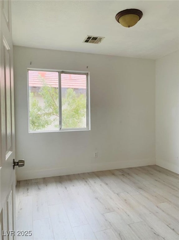 spare room featuring visible vents, light wood-style floors, and baseboards