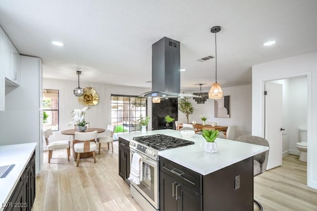 10009 Coral Sands Dr, Las Vegas, NV 89117 - kitchen with island range hood, visible vents, light wood-type flooring, gas stove, and light countertops