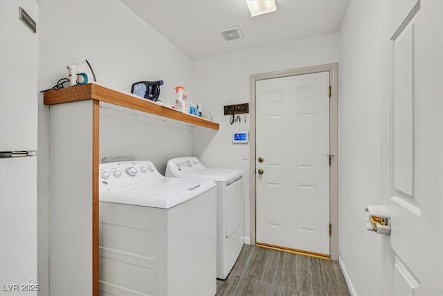 washroom with laundry area, independent washer and dryer, visible vents, wood finished floors, and baseboards