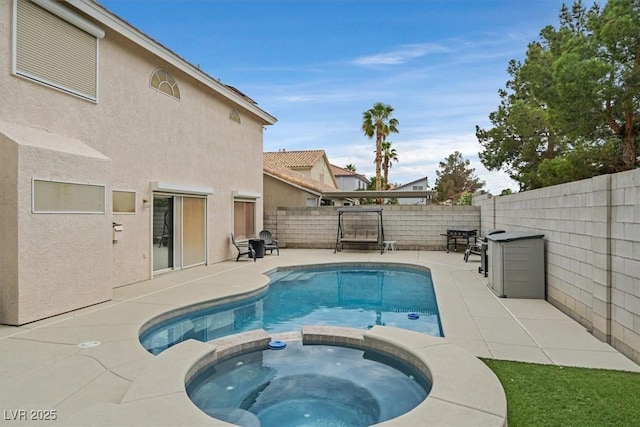 view of swimming pool featuring a patio, a fenced backyard, and a pool with connected hot tub