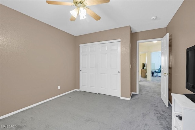 unfurnished bedroom featuring a ceiling fan, baseboards, light colored carpet, and a closet