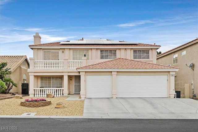 traditional-style house with roof mounted solar panels, central AC unit, a balcony, covered porch, and driveway