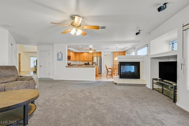 living room with a ceiling fan, visible vents, light carpet, and a fireplace
