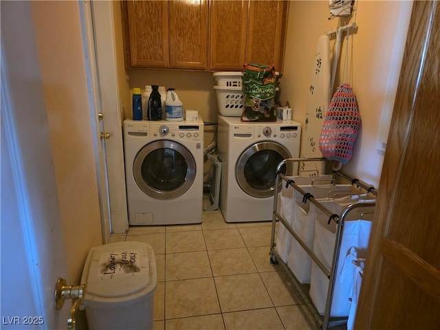 laundry room with cabinet space, light tile patterned flooring, and washer and clothes dryer