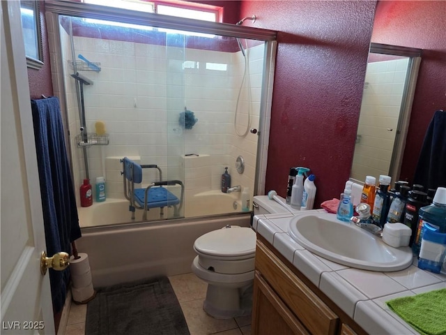bathroom with tile patterned flooring, vanity, a textured wall, toilet, and bath / shower combo with glass door