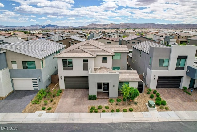 view of front facade featuring an attached garage, a residential view, a mountain view, and stucco siding