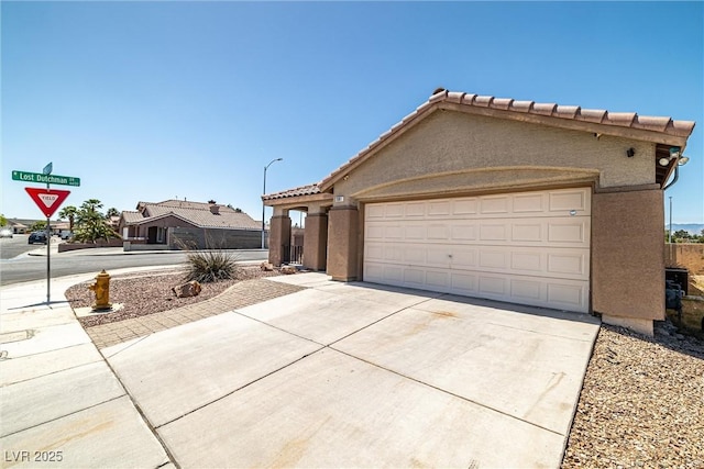 single story home with concrete driveway, a tiled roof, an attached garage, and stucco siding