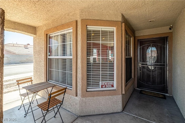 property entrance with a porch and stucco siding