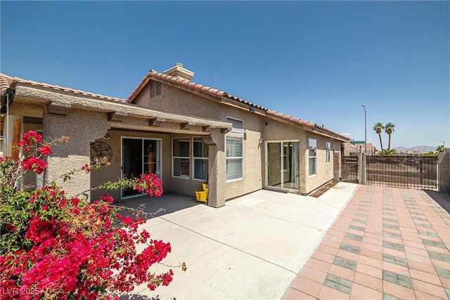 back of property featuring a patio, stucco siding, a tile roof, and fence