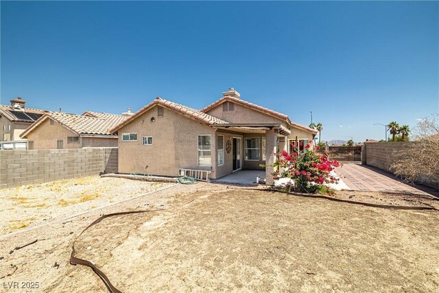 rear view of house with a fenced backyard, a patio area, stucco siding, and a tiled roof