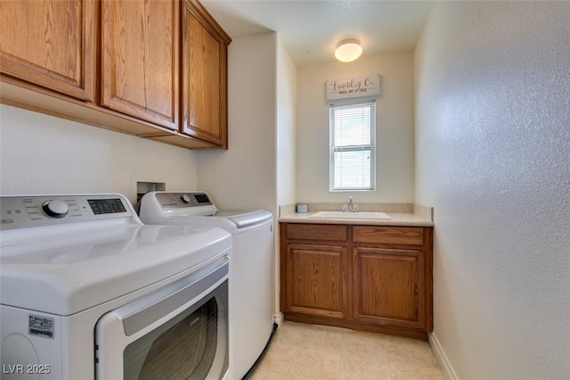 clothes washing area with separate washer and dryer, a sink, cabinet space, and baseboards
