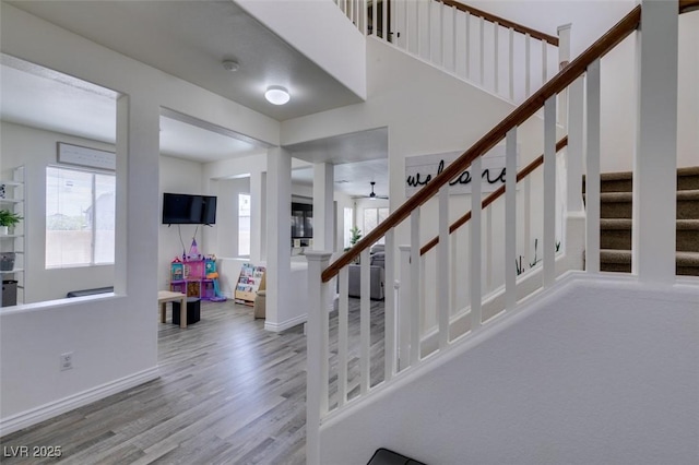 staircase featuring baseboards, ceiling fan, and wood finished floors