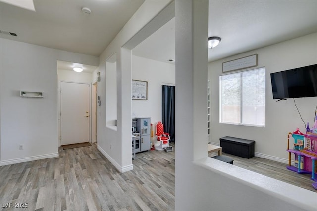 hallway featuring baseboards, visible vents, and wood finished floors
