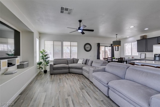 living room featuring ceiling fan, visible vents, baseboards, light wood finished floors, and recessed lighting