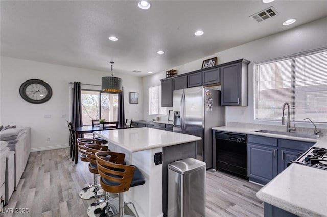 kitchen with a breakfast bar area, visible vents, a center island, a sink, and black dishwasher