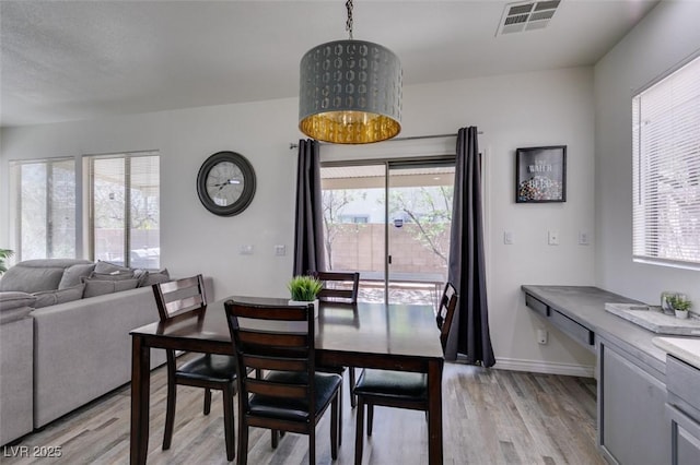 dining area featuring light wood-type flooring, baseboards, visible vents, and a healthy amount of sunlight