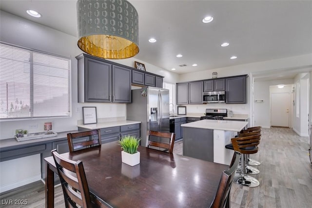 kitchen featuring light countertops, a kitchen island, stainless steel appliances, and light wood-style flooring