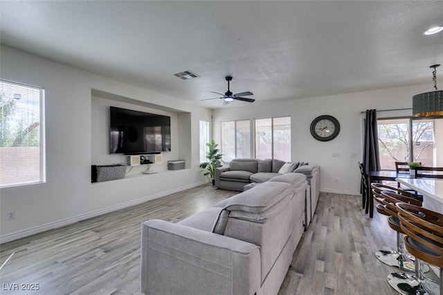 living area featuring a ceiling fan, baseboards, visible vents, and light wood-style floors
